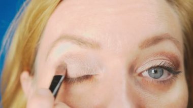 Süper yakın çekim, bir kadının onu göz makyaj yapması göz kapağı gölgeler ile boyar. 4k, ağır çekim