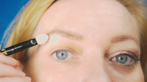 Супер крупный план, женщина делает макияж для глаз, красит веко тенью. 4k, slow motion — стоковое видео