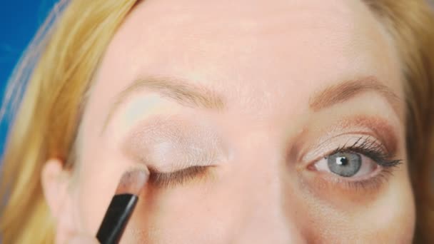 Super close-up, uma mulher fazendo a maquiagem dos olhos, pinta a pálpebra com sombras. 4k, câmera lenta — Vídeo de Stock