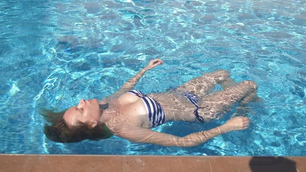 Jeune belle femme inclinable dans un maillot de bain couché dans l'eau à l'extérieur . — Photo
