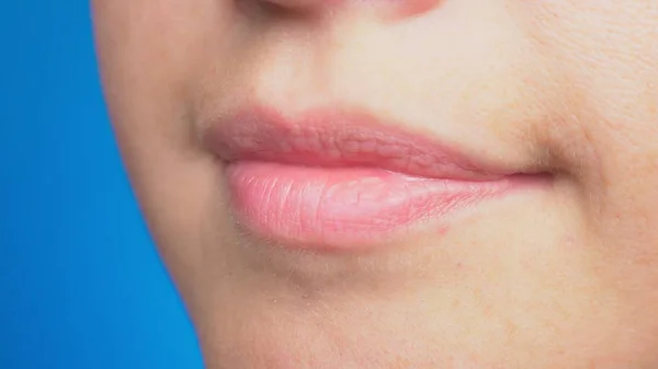 Close-up of smiling lips without makeup, natural beauty, isolated on blue background. — Stock Photo, Image
