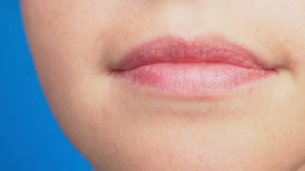 Close-up van glimlachende lippen zonder make-up, natuurlijke schoonheid, geïsoleerd op blauwe achtergrond. — Stockfoto