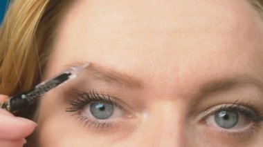 Süper yakın çekim, kadın kaş kalemi kaşları için boyar. 4k, ağır çekim. kadının ona makyaj yapması