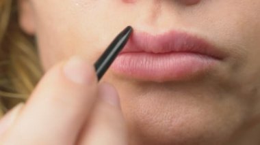 Süper yakın çekim, yavaş hareket, 4k. bir kadın dudaklarını dudaklarının için bir kalemle boyar. Dudak makyaj, dermatolojik hastalık dudaklar cilt üzerinde. Tilki tilki granül