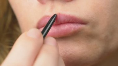 Süper yakın çekim, yavaş hareket, 4k. bir kadın dudaklarını dudaklarının için bir kalemle boyar. Dudak makyaj, dermatolojik hastalık dudaklar cilt üzerinde. Tilki tilki granül
