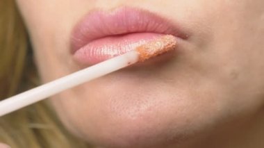 Süper yakın çekim, yavaş hareket, 4k. bir kadının dudakları ile dudak parlatıcısı boyuyor. Dudak makyaj, dermatolojik hastalık dudaklar cilt üzerinde. Tilki tilki granül