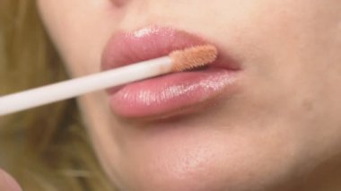 Süper yakın çekim, yavaş hareket, 4k. bir kadının dudakları ile dudak parlatıcısı boyuyor. Dudak makyaj, dermatolojik hastalık dudaklar cilt üzerinde. Tilki tilki granül