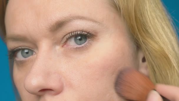 Närbild. 4k, slowmotion. kvinna tillämpa kosmetiska med en stor borste. en flicka målar kinderna med Rouge. makeup. — Stockvideo
