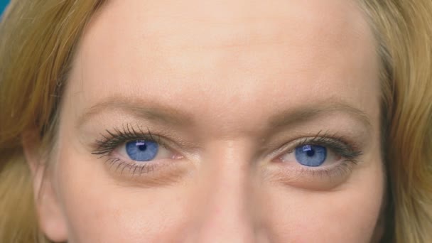 Vackra blå ögon närbild. En ung kvinna blinkar och tittar på kameran. 4 k, närbild, slow motion — Stockvideo