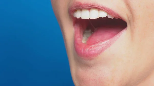 Close-up, lábios femininos sem maquiagem, em um fundo azul. a emoção da surpresa . — Fotografia de Stock