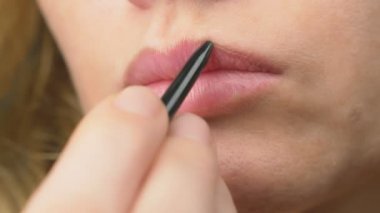 Süper yakın çekim, yavaş hareket, 4k. bir kadın dudaklarını dudaklarının için bir kalemle boyar. Dudak makyaj, dermatolojik hastalık dudaklar cilt üzerinde. Tilki tilki granül