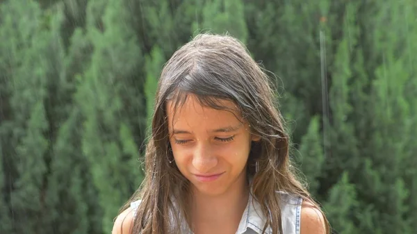 Молодая грустная брюнетка с длинными волосами, стоящая под проливным дождем без зонта. макро — стоковое фото