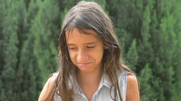 Giovane ragazza triste bruna con i capelli lunghi in piedi sotto la pioggia battente senza ombrello. primo piano — Foto Stock