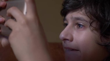 Sevimli genç çocuk odasına gece, bir smartphone kullanarak yatakta yatıyordu. telefonunu metni okur. Gözlerini kapat