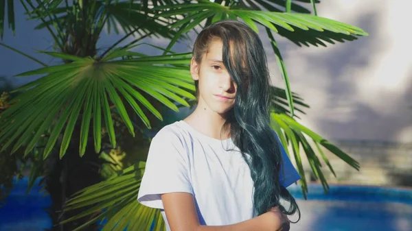 Bela menina morena posando contra um fundo de folhas de palma. Uma adolescente com cabelo encaracolado longo azul. verão dia ensolarado . — Fotografia de Stock