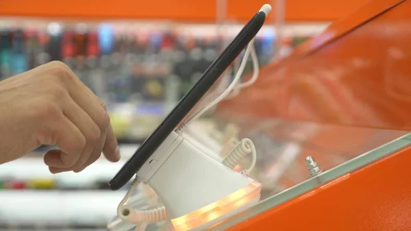 O comprador na loja de eletrônicos escolhe um novo gadget. close-up, fundo desfocado. Procurando uma nova paz de gadget . — Fotografia de Stock