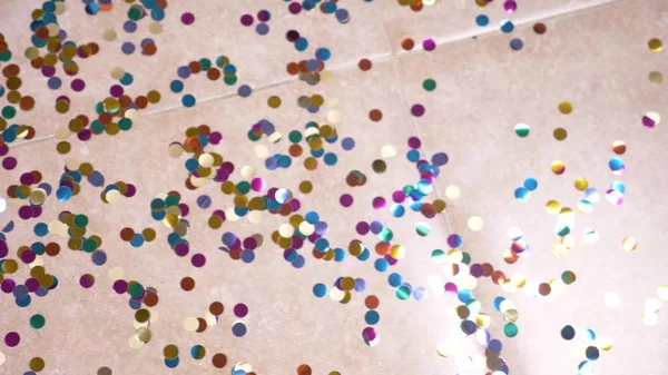 Round multicolored confetti lie on the tiled floor. — Stock Photo, Image