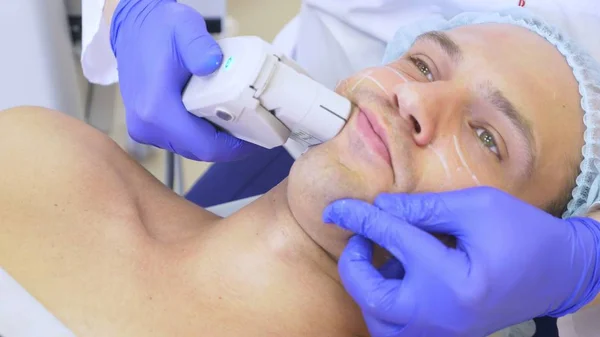 Non-surgical face lifting. SMAS lifting ultrasonic. The process of rejuvenation. Hardware cosmetology. contour face plastic. hands of a dermatologist doctor make a man an ultrasound facelift — Stock Photo, Image