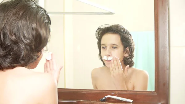 Nastolatek goli, po raz pierwszy, nastoletni chłopiec stosowanie pianki do golenia, Pielęgnacja skóry, krem do twarzy, — Zdjęcie stockowe