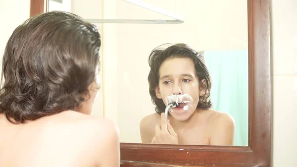 Підліток голиться перший раз, хлопчик-підліток застосовує піну для гоління, скінкард, крем, обличчя , — стокове фото
