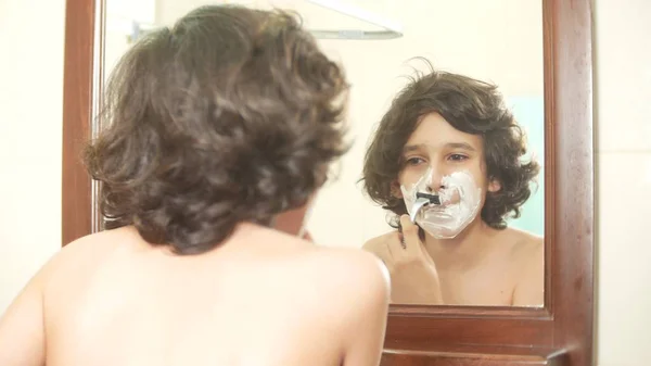 Підліток голиться перший раз, хлопчик-підліток застосовує піну для гоління, скінкард, крем, обличчя — стокове фото