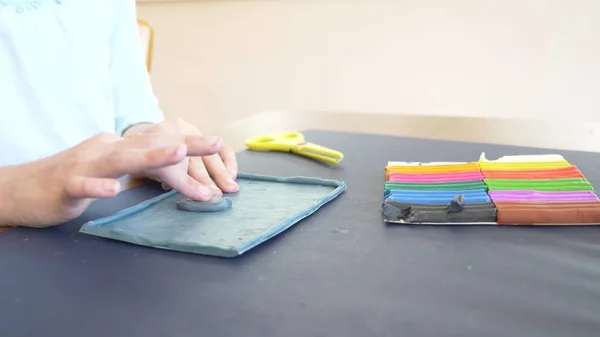 La chica sentada en la mesa, dibuja diferentes figuras de plastilina modelo de color. Desarrollo del modelado artístico en niños. primer plano , — Foto de Stock