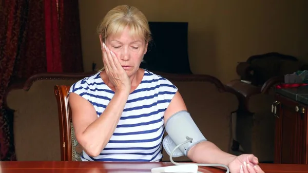 Bejaarde vrouw meten van de bloeddruk. Een oude vrouw zitten in zijn huis aan de tafel. kopie ruimte — Stockfoto