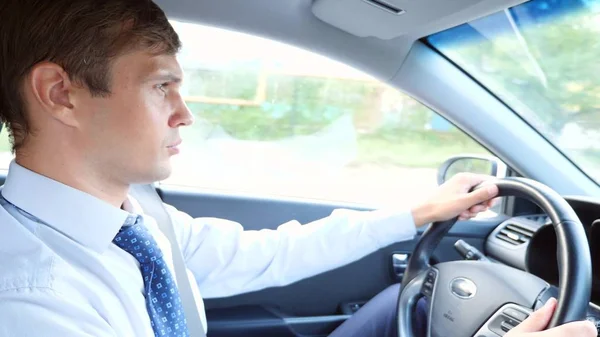 Un hombre de negocios con camisa y corbata habla con el pasajero, distraído de la carretera. violación de las normas de tráfico . — Foto de Stock