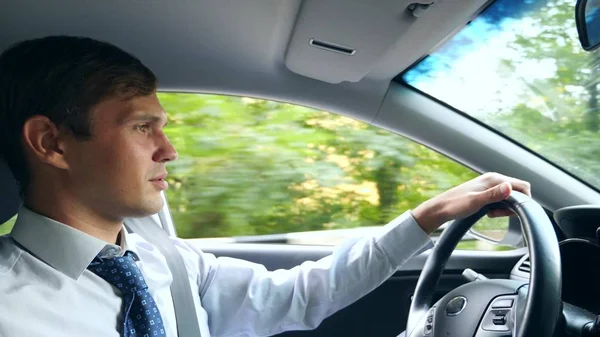 Un hombre de negocios con camisa y corbata habla con el pasajero, distraído de la carretera. violación de las normas de tráfico . — Foto de Stock