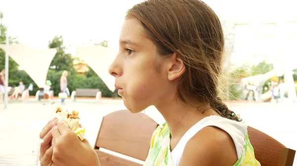 Uma menina atraente come pão fresco pita pão com uma salada de legumes frescos e carne, sentado em um café fast food sob uma árvore no parque. . — Fotografia de Stock