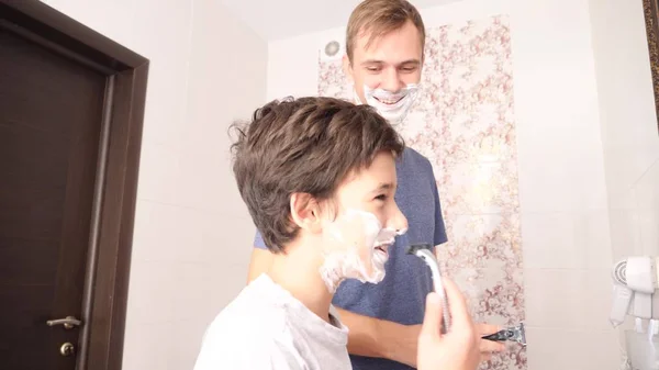 Батько і син у ванній кімнаті вранці, маленький хлопчик копіює свого батька, голиться . — стокове фото