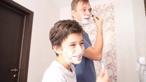 Батько і син у ванній кімнаті вранці, маленький хлопчик копіює свого батька, голиться . — стокове фото