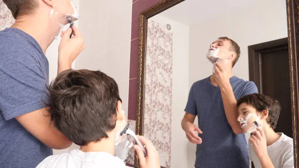 Father and son in the bathroom in the morning, little boy copies his father shaving. — Stock Photo, Image