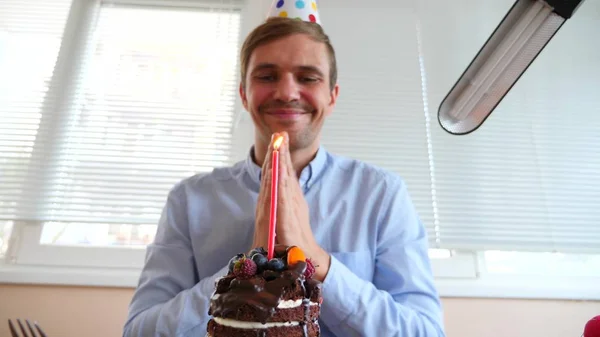 De freelancer viert de vakantie, hij zit alleen aan de tafel en eet een vakantie-taart. — Stockfoto