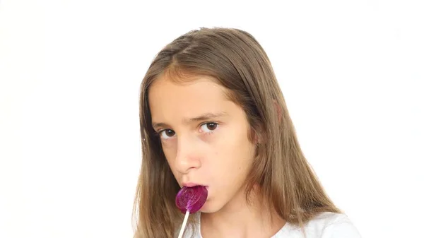 一个小女孩舔了一根棒糖盯着相机, 并制作滑稽的面孔。复制空间 — 图库照片