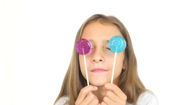 A little girl licks a lollipop stares into the camera and makes funny faces. copy space — Stock Photo, Image