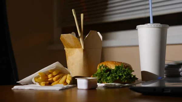 Uma mesa de homens de negócios com uma xícara descartável para café e fast food. Abre um portátil. Jantar atrasado no escritório. espaço de cópia — Fotografia de Stock