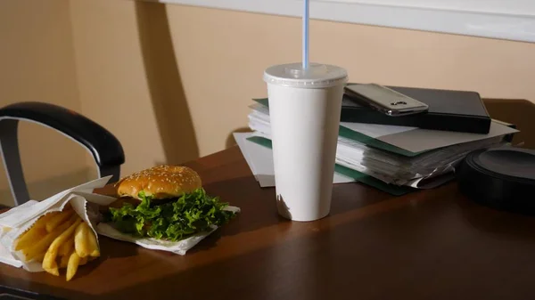 Uma mesa de homens de negócios com uma xícara descartável para café e fast food. Abre um portátil. Jantar atrasado no escritório. espaço de cópia — Fotografia de Stock