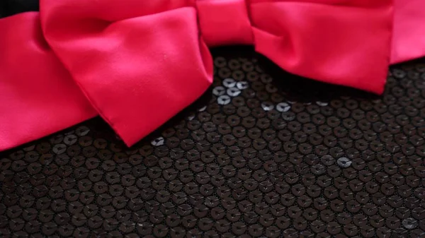 Fabric as background. black knitted fabric with paillettes. scarlet bow — Stock Photo, Image