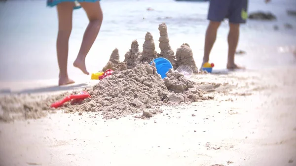 Castelo de areia na praia, uma família irreconhecível faz um castelo de areia em uma praia pública. borrão — Fotografia de Stock