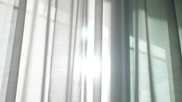 A transparent curtain on the window, gently moved by the wind. sunlight