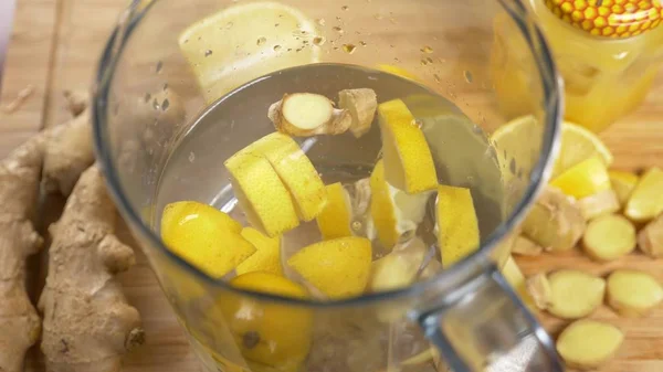 someone makes a handmade drink from lemons, ginger root and pineapple