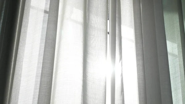 A transparent curtain on the window, gently moved by the wind. sunlight