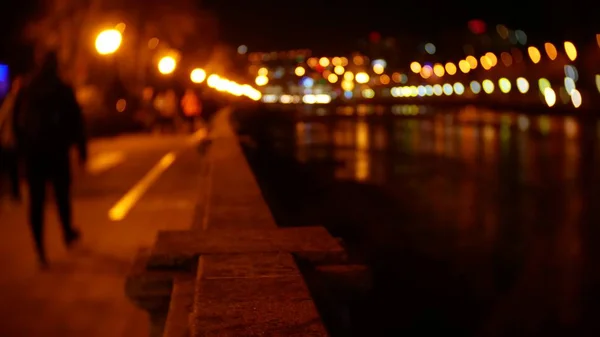 人们沿着堤岸漫步, 到处都是夜灯。模糊。散景 — 图库照片