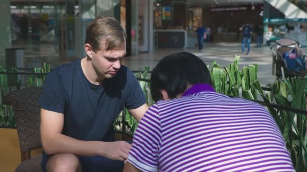 Nahaufnahme, Treffen in einem Café. Männer diskutieren im Café eines großen Einkaufskomplexes über Geschäfte — Stockvideo