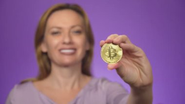 arka plan beyaz dişli bir gülümseme ile genç bir kadın bulanık, onun elinde bir bitcoin altın madeni para almıştır. Bitcoin netlik. renk arka plan