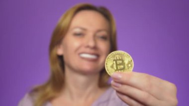 arka plan beyaz dişli bir gülümseme ile genç bir kadın bulanık, onun elinde bir bitcoin altın madeni para almıştır. Bitcoin netlik. renk arka plan