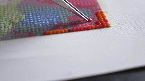The mosaic process, the girls hand holding tweezers, making a mosaic.