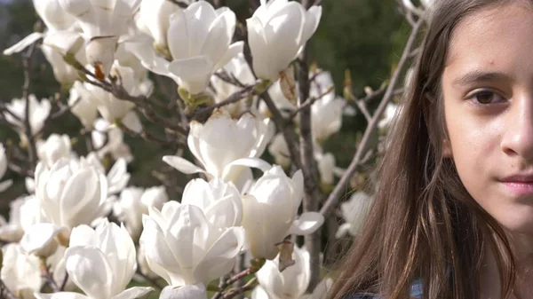 Prachtige tienermeisje op witte magnolia bloemen achtergrond in de tuin. schittering van de zon — Stockfoto