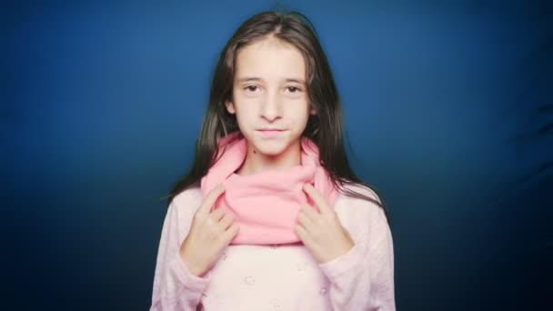 Красивая девушка-подросток в осенней одежде, позирует перед камерой на синем фоне — стоковое видео